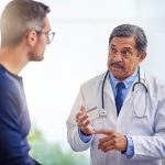 Qualified medical examiner talks with a man injured at work