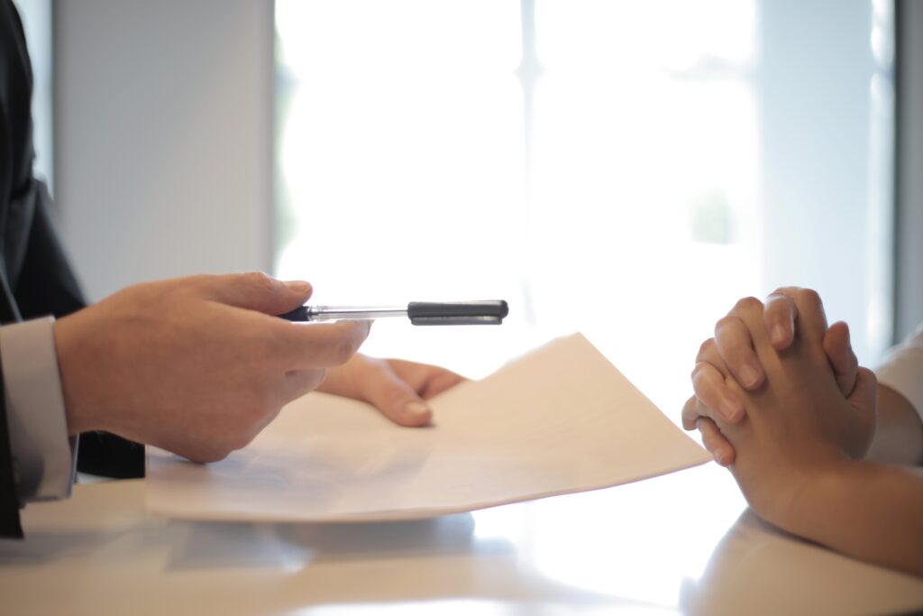 Professional handing pen and document to client during consultation for securing medical benefits in Pomona workers compensation claims California
