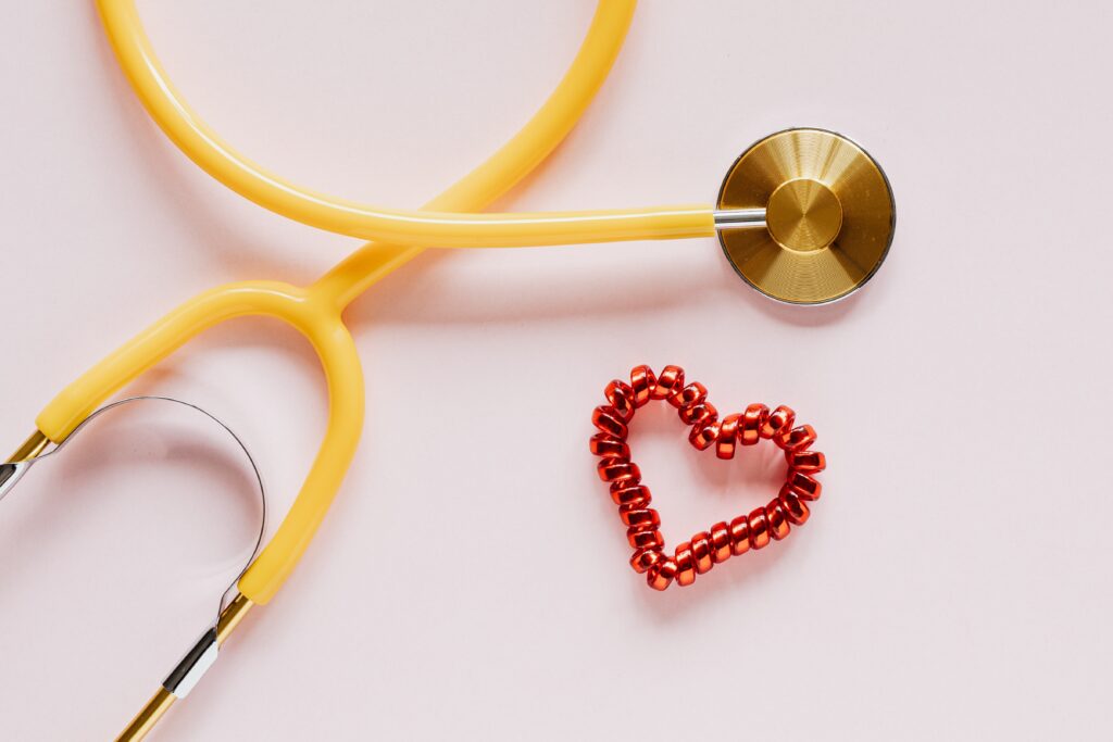 Yellow stethoscope arranged in heart shape next to red pill heart symbolizing caring medical benefits in California workers compensation law Pomona