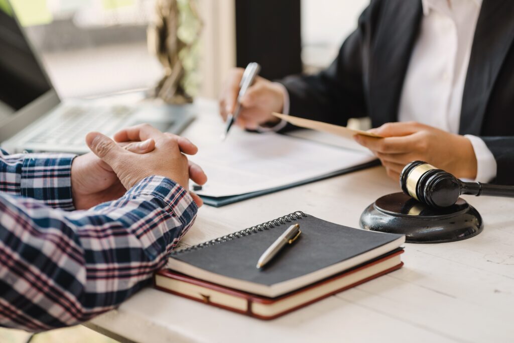 Professional lawyer in suit discussing legal documents with client using gavel and notebooks employee misclassification consultation in Sherman Oaks California